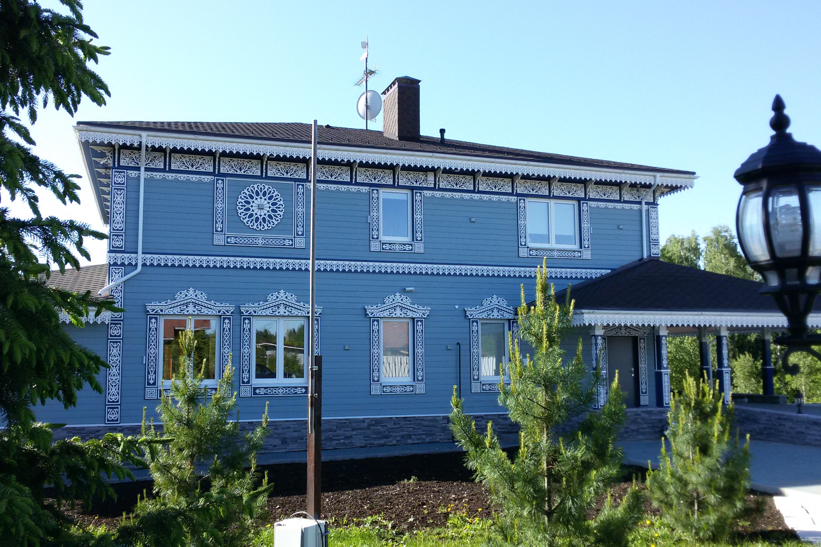 Белые резные деревянные наличники на голубом фасаде